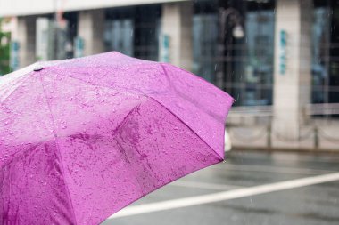 Kötü hava. Yağmurlu bir gün. Şehir arka planında yağmur damlaları olan bir şemsiye. Şehir tarzı..
