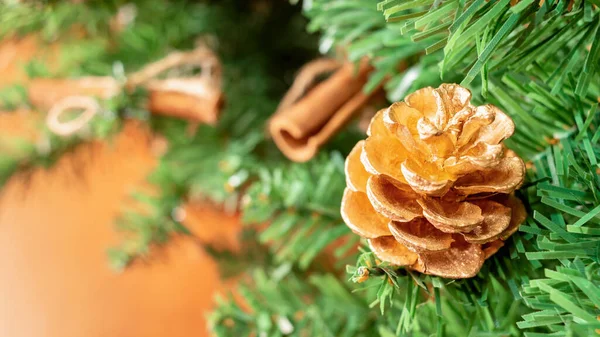 Altın kozalaklı bir Noel ağacı ve bulanık arka planda tarçın çubukları. Kopyalama alanı ile.