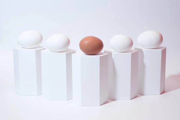 Sanat kompozisyonu, beyaz arka planda beyaz ve kahverengi yumurta. Beyaz geometrik şekiller ve yumurtalar. Minimalist kompozisyon. Paskalya tatili