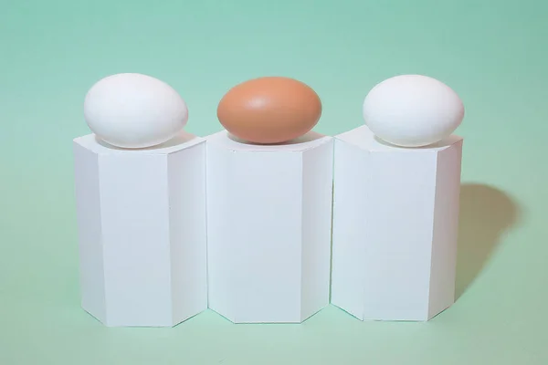 Sanat kompozisyonu, yeşil arka planda beyaz ve kahverengi yumurta. Beyaz geometrik şekiller ve yumurtalar. Minimalist kompozisyon. Paskalya tatili