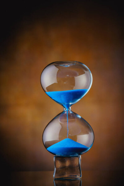 blue sand hourglass on old background