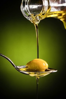 Zeytinyağı ve kaşık üzerinde yeşil zeytin