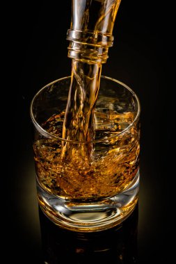 Siyah arka planda bir bardak viski.