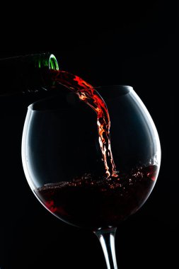 Siyah arka planda kırmızı şarap ve şişe.