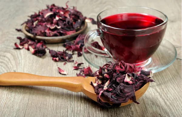 Hibiscus tea. Hibiscus tea in a wooden spoon on a background of a cup of fresh tea. Vitamin tea for cold and flu.