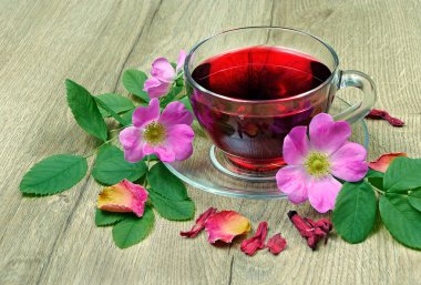 Ebegümeci çayı bir cam bardak ve ahşap bir masa üzerinde çiçekli dogrose. Vitamini çay soğuk algınlığı ve grip için.