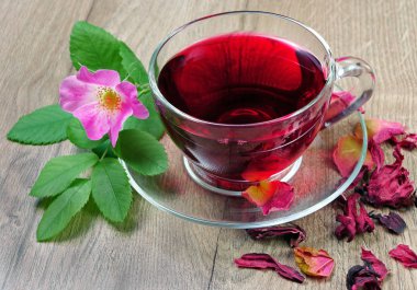 Ebegümeci çayı bir cam bardak ve ahşap bir masa üzerinde çiçekli dogrose. Vitamini çay soğuk algınlığı ve grip için.