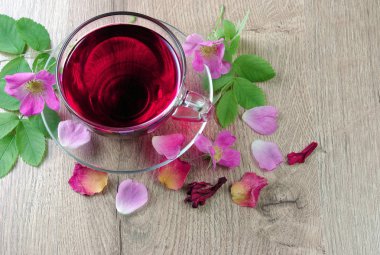 Ebegümeci çayı bir cam bardak ve ahşap bir masa üzerinde çiçekli dogrose. Vitamini çay soğuk algınlığı ve grip için.