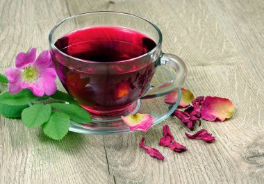 Ebegümeci çayı bir cam bardak ve ahşap bir masa üzerinde çiçekli dogrose. Vitamini çay soğuk algınlığı ve grip için.