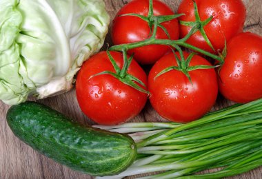 taze olgun sebze - domates, lahana, yeşil soğan ve salatalığın üzerinde ahşap bir masa. 