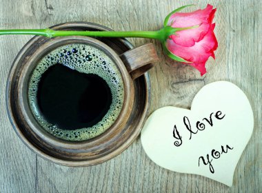 Günaydın. bir fincan kahve ve bir ahşap masa üzerinde kırmızı bir gül