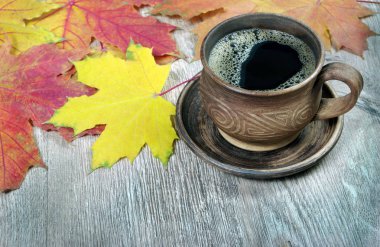 fincan kahve ve sarı akçaağaç ahşap bir masaya bırakır