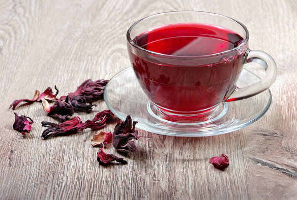 Hibiscus tea. Hibiscus tea in a wooden spoon on a background of a cup of fresh tea. Vitamin tea for cold and flu.