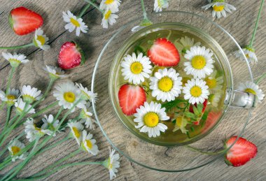 papatya ve çilek çayı üzerinde ahşap bir masa. vitaminler bitkisel çay. üstten görünüm.