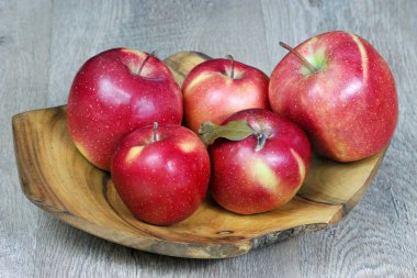 ahşap bir tabak üzerinde olgun kırmızı elmalar