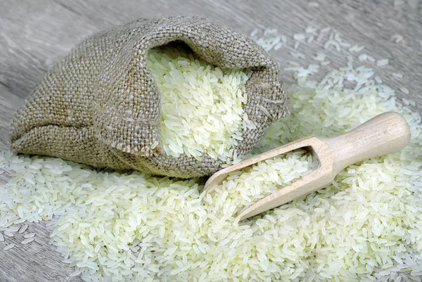 rice cereal in a scoop on a wooden table. sack of rice and scoop. copy spaces