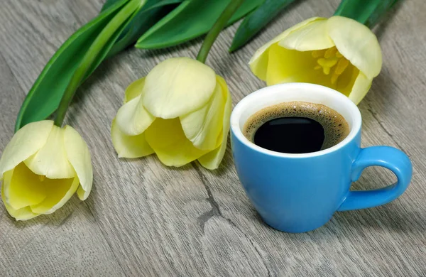 cup of coffee and tulips on wooden table. copy spaces.