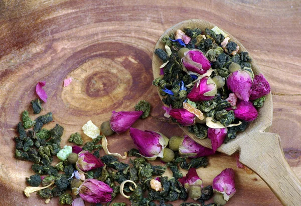 花放在一个木勺在一个黑暗的木桌上 绿茶与花和干果片 混合茶 顶视图 — 图库照片