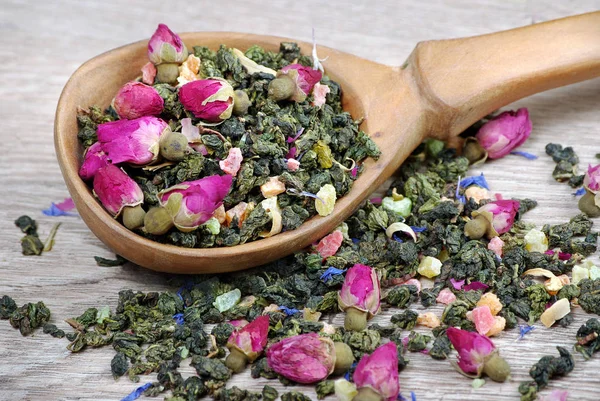 花放在木桌上的木勺里 绿茶与花和干果片 混合茶 顶视图 — 图库照片