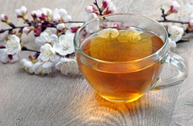 Tahta bir masada bir fincan çay ve bahar çiçekleri