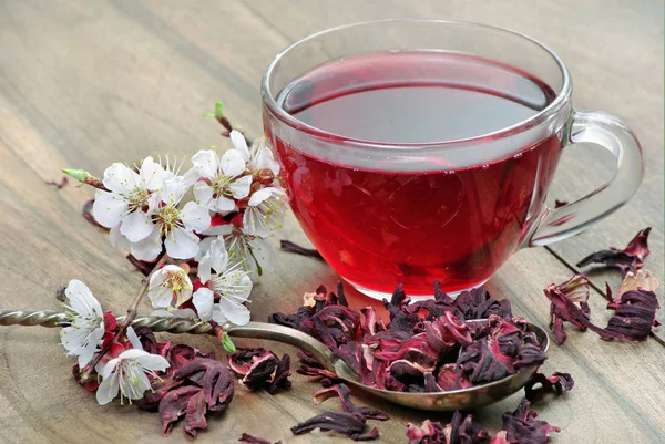 cup of hibiscus tea and spring flowers on a wooden table. herbal tea for cold and flu