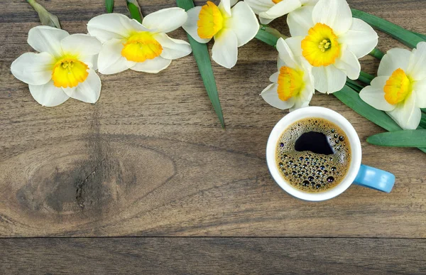 spring flowers and a cup of coffee on a wooden table. copy spaces