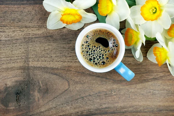 spring flowers and a cup of coffee on a wooden table. copy spaces