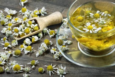 Tahta bir masada bir fincan papatya çayı. Bitki çayı. Soğuk algınlığı ve grip ilacı.