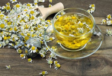 Tahta bir masada bir fincan papatya çayı. Bitki çayı. Soğuk algınlığı ve grip ilacı.