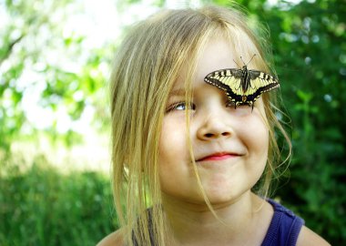 Kelebek bir çocuğun üzerinde oturuyor. Kelebekli çocuk. Kelebek machaon küçük bir kız üzerinde. Seçici odak. Kırlangıç kuyruğu kelebeği, Papilio maçaonu.