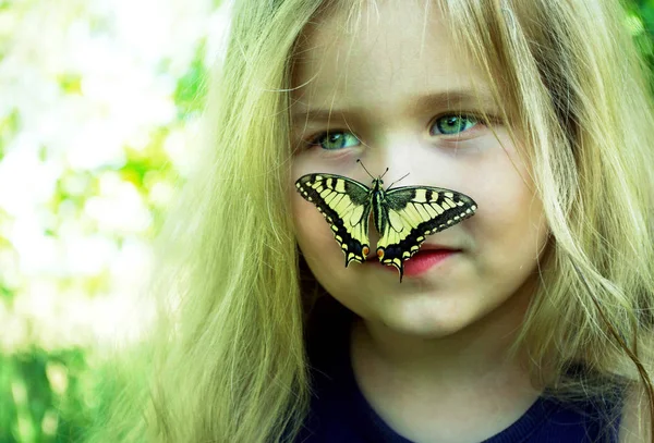 Kelebek bir çocuğun üzerinde oturuyor. Kelebekli çocuk. Kelebek machaon küçük bir kız üzerinde. Seçici odak. Kırlangıç kuyruğu kelebeği, Papilio maçaonu.