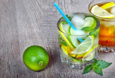 serinletici içecek bardak. ahşap bir masa üzerinde buz, kekik, nane ve limon ile soğuk su cam.