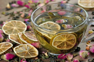 ahşap bir masa üzerinde çay ve kurutulmuş limon fincan. kurutulmuş gül çiçekleri ile yeşil çay.