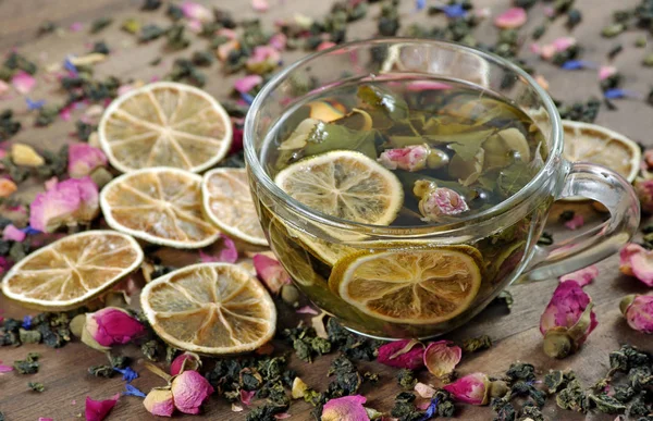ahşap bir masa üzerinde çay ve kurutulmuş limon fincan. kurutulmuş gül çiçekleri ile yeşil çay.