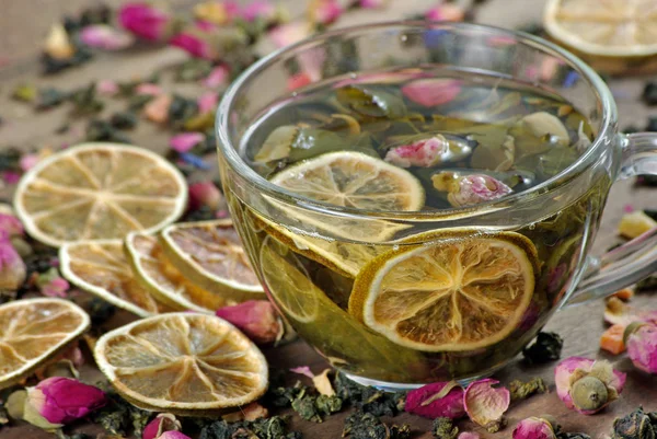 cup of tea and dried lemons on a wooden table. green tea with dried rose flowers.