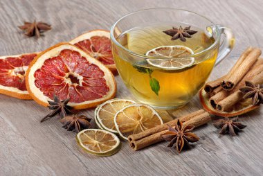 limon, kurutulmuş situs, anason yıldız ve tarçın ahşap bir masa üzerinde sopa ile bitkisel çay fincan. soğuk algınlığı ve grip için sıcak çay