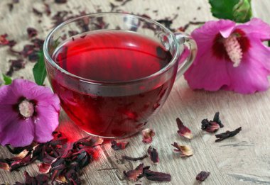 ahşap bir masada ebegümeci çayı fincan. ebegümeci çiçek, kuru limon, tarçın ve taze vitamin içecek bir fincan.