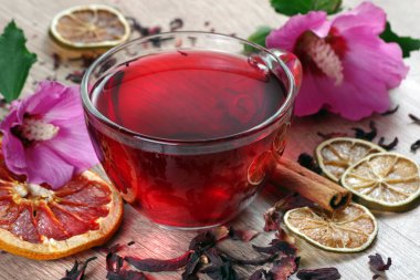 ahşap bir masada ebegümeci çayı fincan. ebegümeci çiçek, kuru limon, tarçın ve taze vitamin içecek bir fincan.