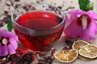 ahşap bir masada ebegümeci çayı fincan. ebegümeci çiçek, kuru limon, tarçın ve taze vitamin içecek bir fincan.