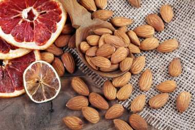 bir kaşık badem fındık ve ahşap bir masada kurutulmuş meyve yakın. badem, anason yıldız ve kurutulmuş greyfurt