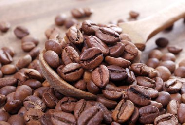 bir kaşık kahve çekirdekleri. tahta bir masada bir kaşık kavrulmuş kahve çekirdekleri.