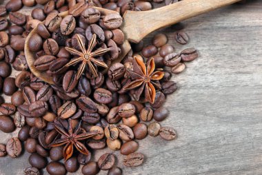 bir kaşık kahve çekirdekleri. bir kaşık, anason yıldız ve tarçın ahşap bir masada kavrulmuş kahve çekirdekleri. kahve ve baharatlar.