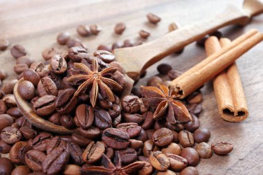 bir kaşık kahve çekirdekleri. bir kaşık, anason yıldız ve tarçın ahşap bir masada kavrulmuş kahve çekirdekleri. kahve ve baharatlar.