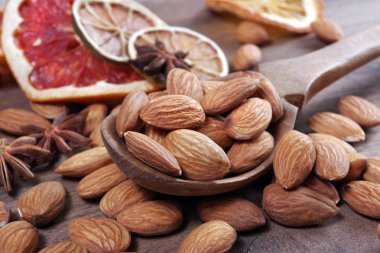 bir kaşık badem fındık ve ahşap bir masada kurutulmuş meyve yakın. badem, anason yıldız ve kurutulmuş greyfurt