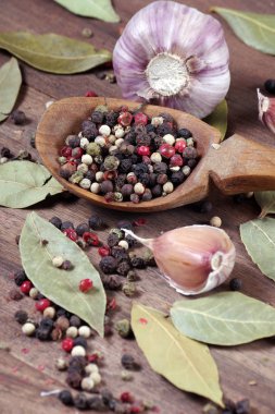 Mutfak için geleneksel baharatlar. Koyun yaprağı, kaşıkta çeşitli biberler ve ahşap bir masada sarımsak karışımı. Üst Manzara. Boşlukları kopyala
