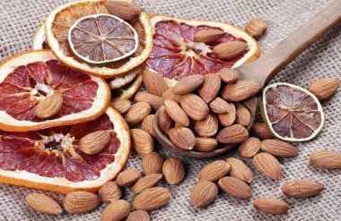 Bir kaşıkta badem fıstığı ve masada kurutulmuş meyveler.