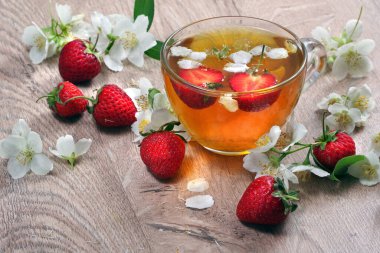 Yaz vitamin çayı. Tahta bir masada yasemin ve çilekli yeşil çay. Kapat.