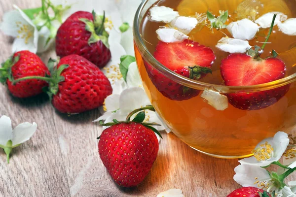 summer vitamin tea. green tea with jasmine and strawberries on a wooden table. close up