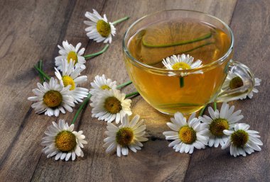 yaz bitkisel çayı. Tahta bir masada papatya çayı ve papatya çiçeği.