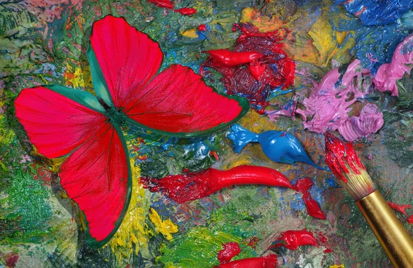 red color concept. bright red morpho butterfly on the artist\'s palette. art paints and butterfly colorful background